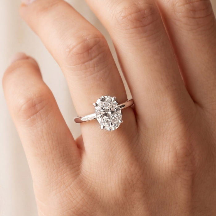 Close-up van de ovale solitaire verlovingsring 2.0 ct in 14k witgoud aan de hand, op ware grootte (steen 10,5 mm)
