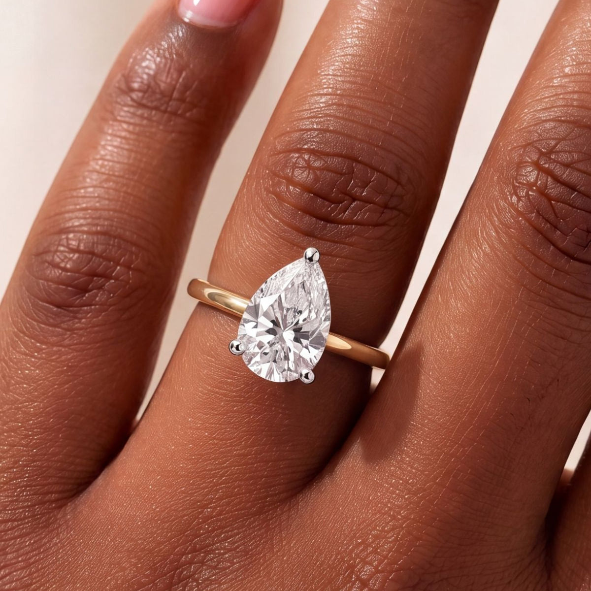 Close-up van de peervormige solitaire verlovingsring 2.0 ct in 14k geelgoud aan de hand