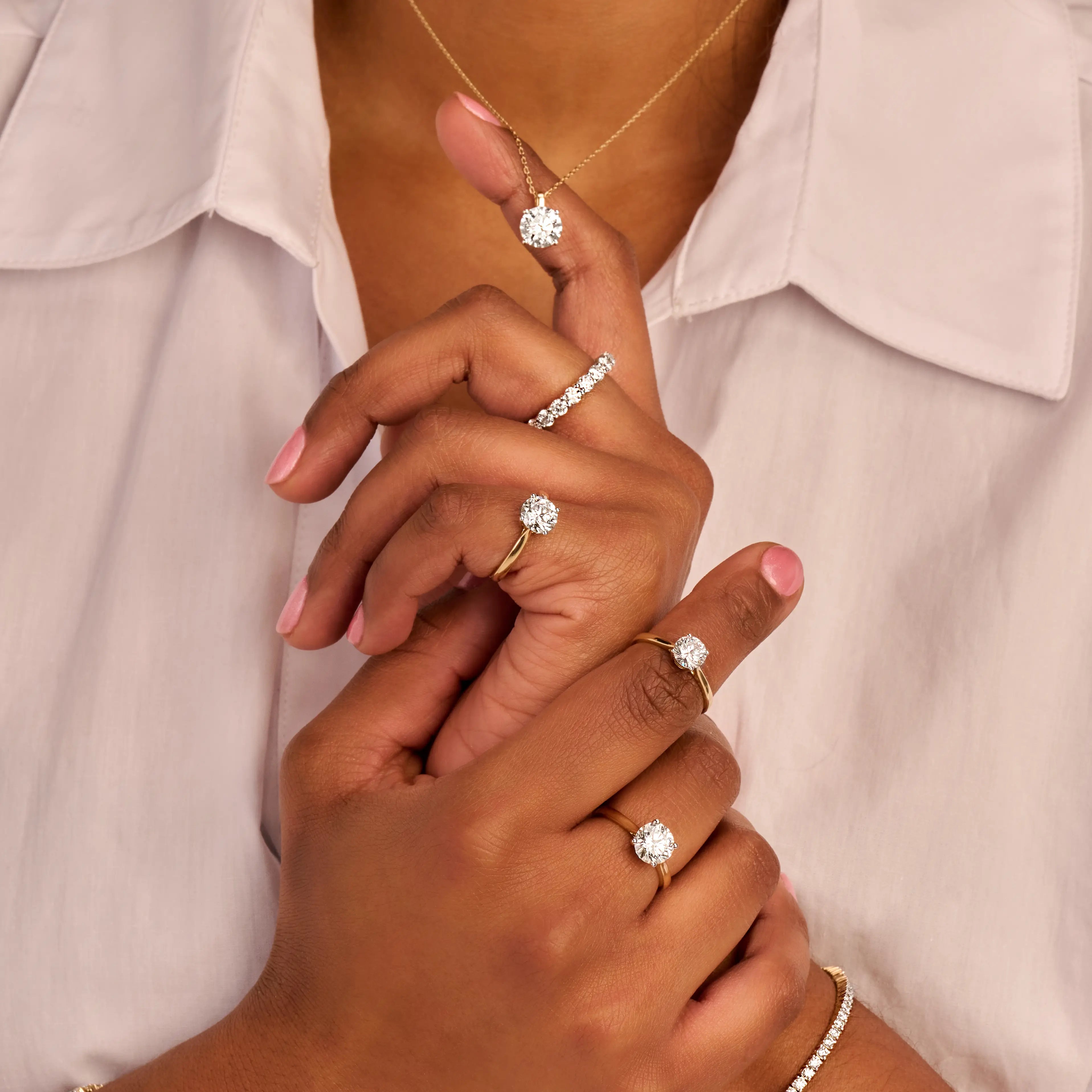 Een gestyled modelbeeld dat veel 14k gouden sieraden draagt waaronder solitaire ringen met 1.0, 1.5 en 2.0ct diamanten. Daarbij armbanden en eeuwigheid ring