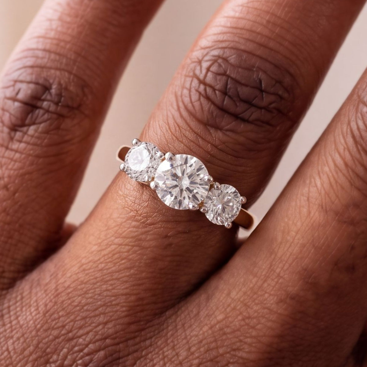 Close-up van de ronde trilogie verlovingsring 2.0 ct in 14k geelgoud aan de hand