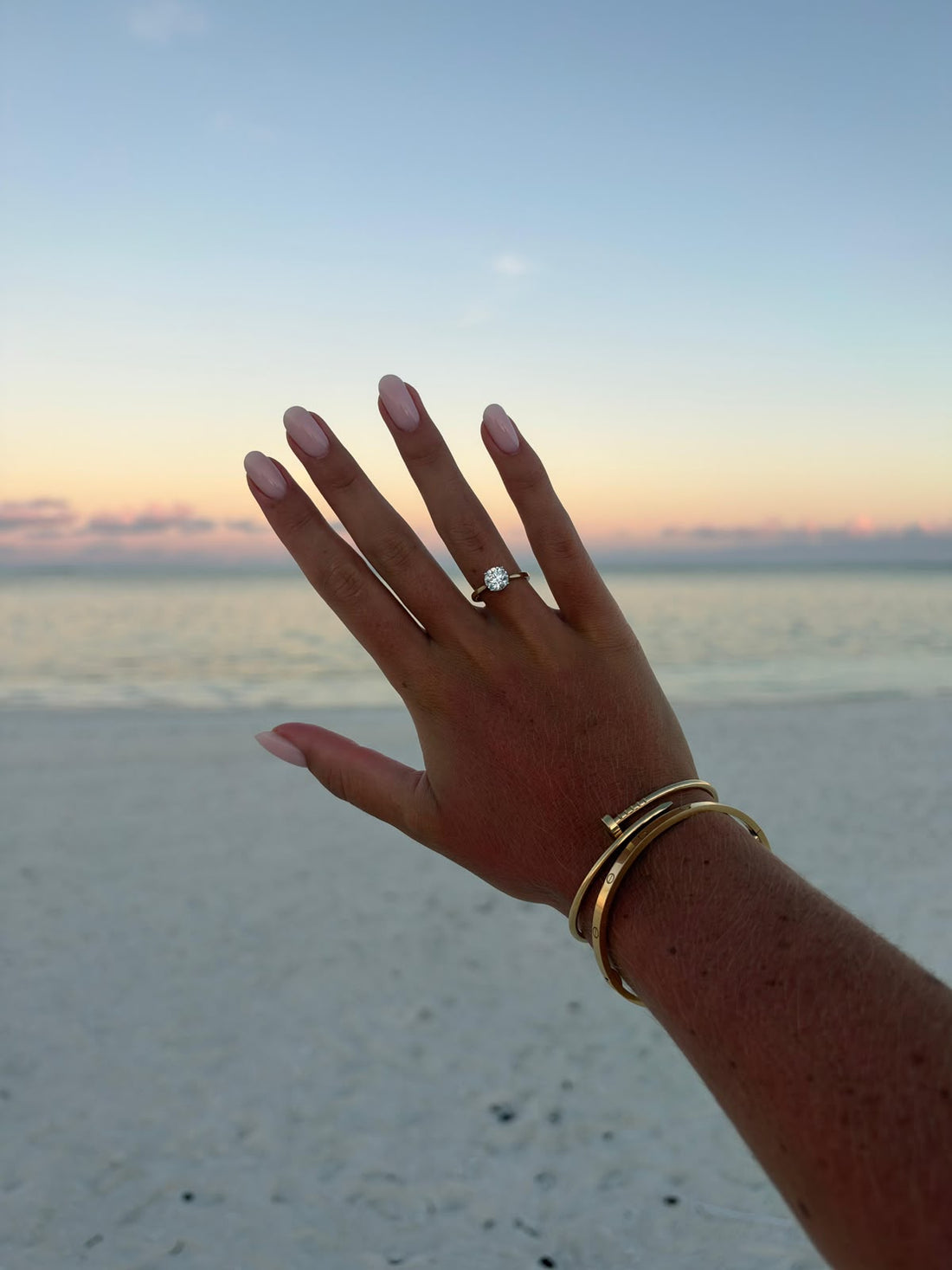 Klantfoto van Jordi: solitaire ring in geelgoud aan de hand bij zonsondergang op het strand