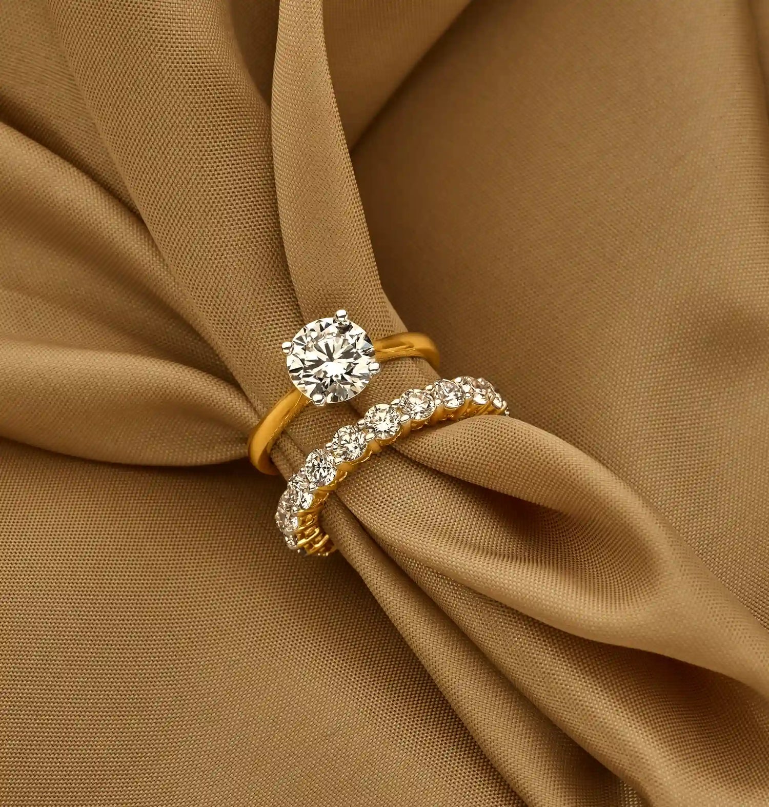 Sfeerbeeld van een solitaire ring 2.0 ct diamant met 14k geelgoud en een eternity ring 3.0 ct diamant op stof