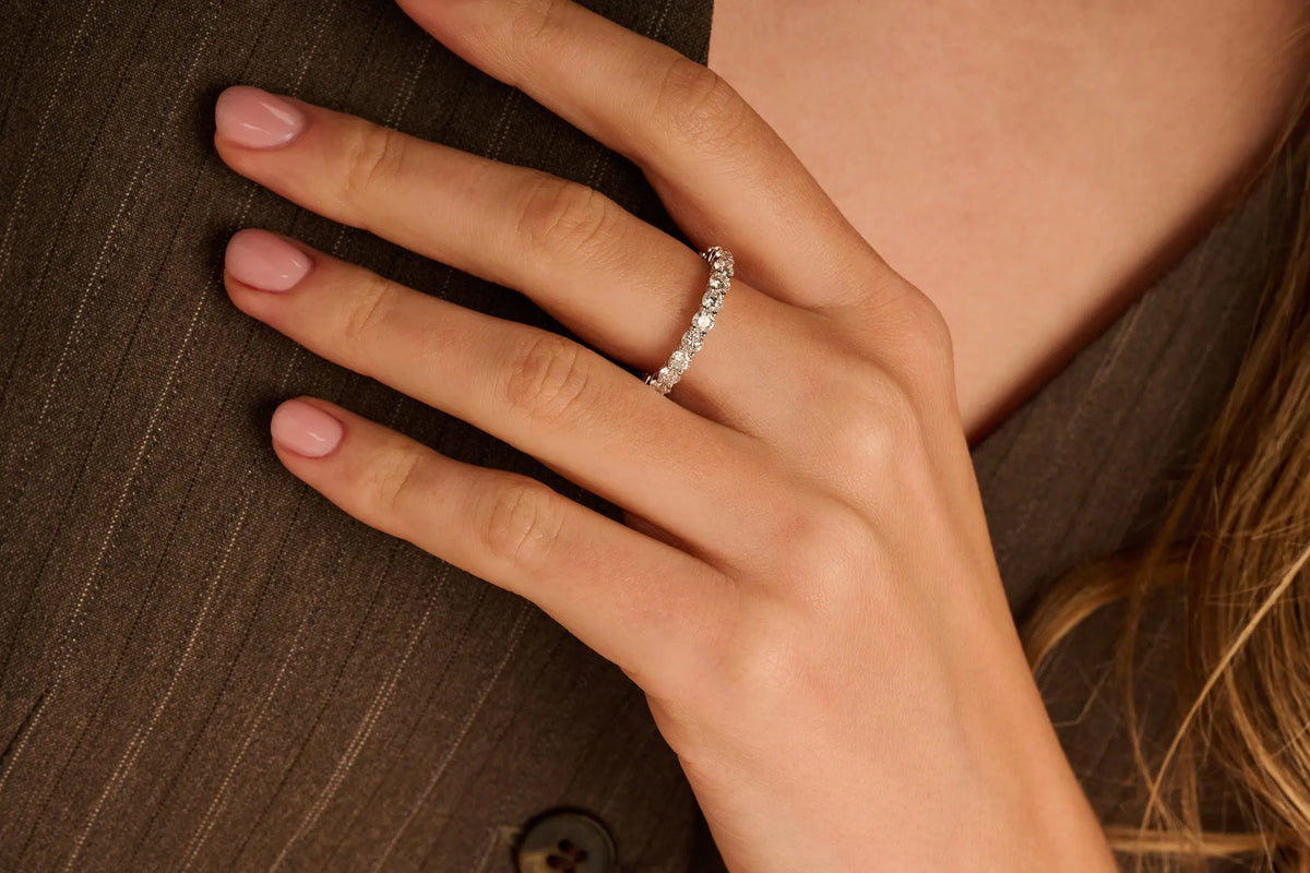 Model draagt een 14k gouden eternity ring van Louen DIamonds met een 2.0ct diamanten in witgoud ingezoomd op donkere kleding ingezoomd op hand