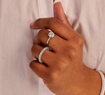 Inngezoomed modelbeeld met een 14k witgouden eternity ring van 3ct diamant om hand met daarbij een solitaire ring van 1.5 ct