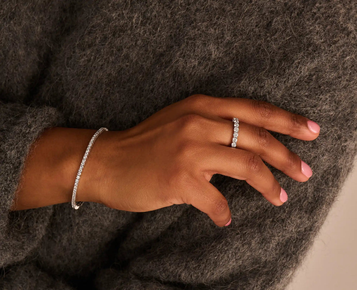 Louen diamonds eternity ring van 14k witgoud met 3ct lab grown diamant op model samen met een tennisarmband geelgoud diamant op wollen trui