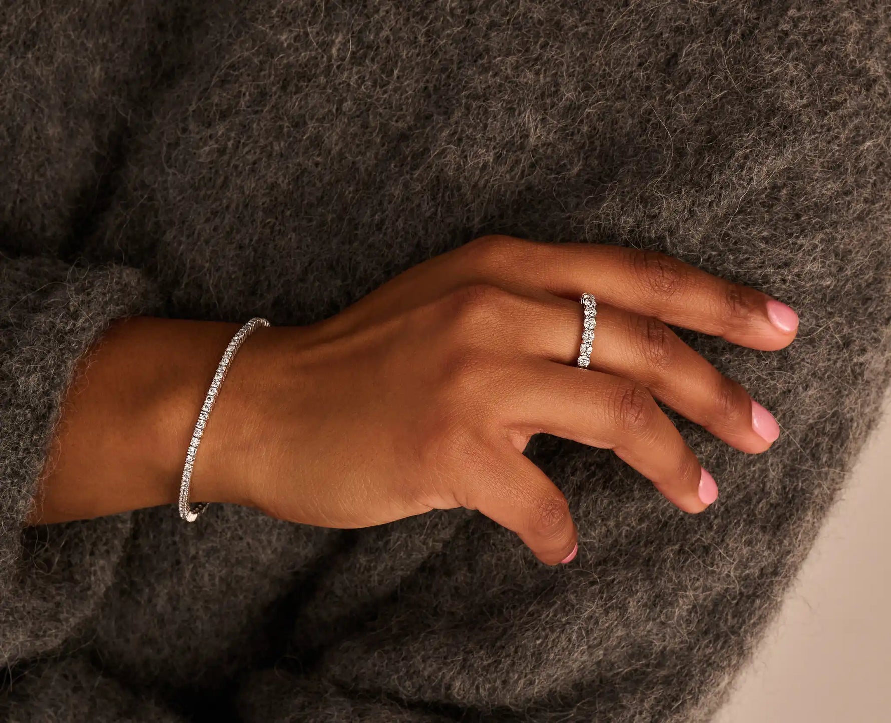 Louen diamonds eternity ring van 14k witgoud met 3ct lab grown diamant op model samen met een tennisarmband geelgoud diamant op wollen trui