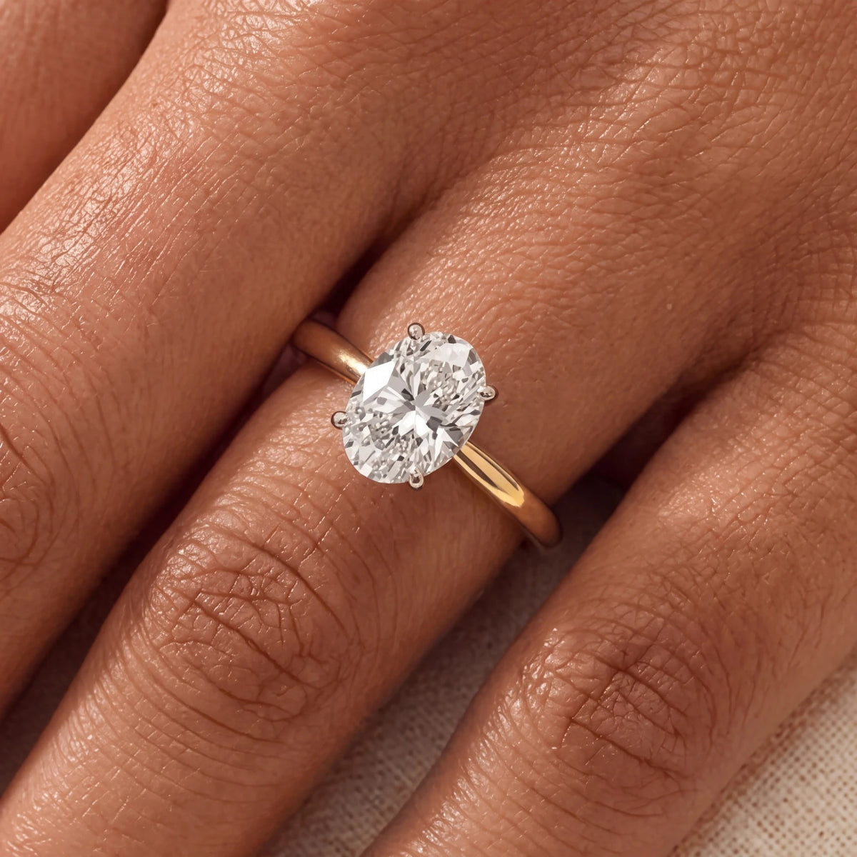 Ovale solitaire verlovingsring 1.5 ct in 14k geelgoud aan de hand, op ware grootte (steen 9,5 mm)