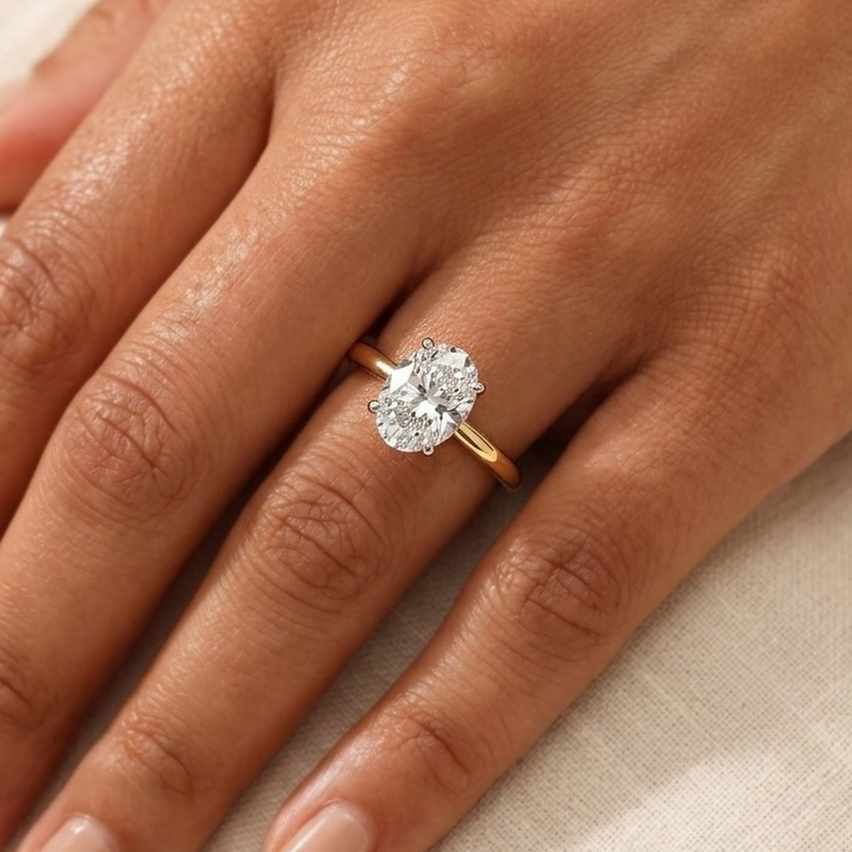 Close-up van de ovale solitaire verlovingsring 2.0 ct in 14k geelgoud aan de hand