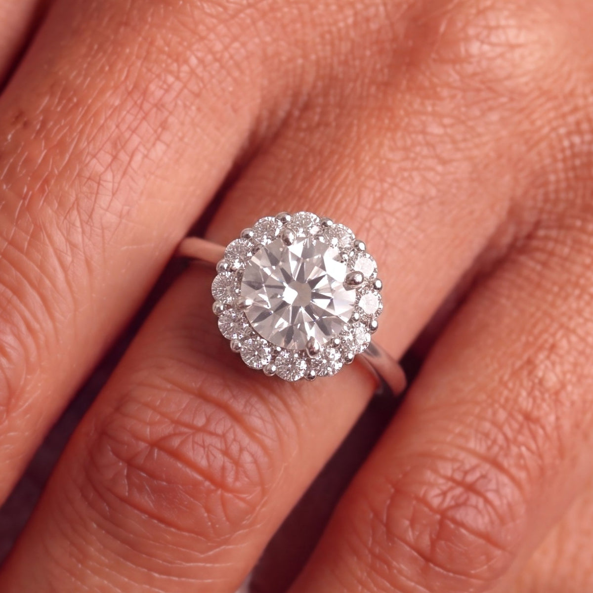 Close-up van de ronde halo verlovingsring 1.5 ct in 14k witgoud aan de hand