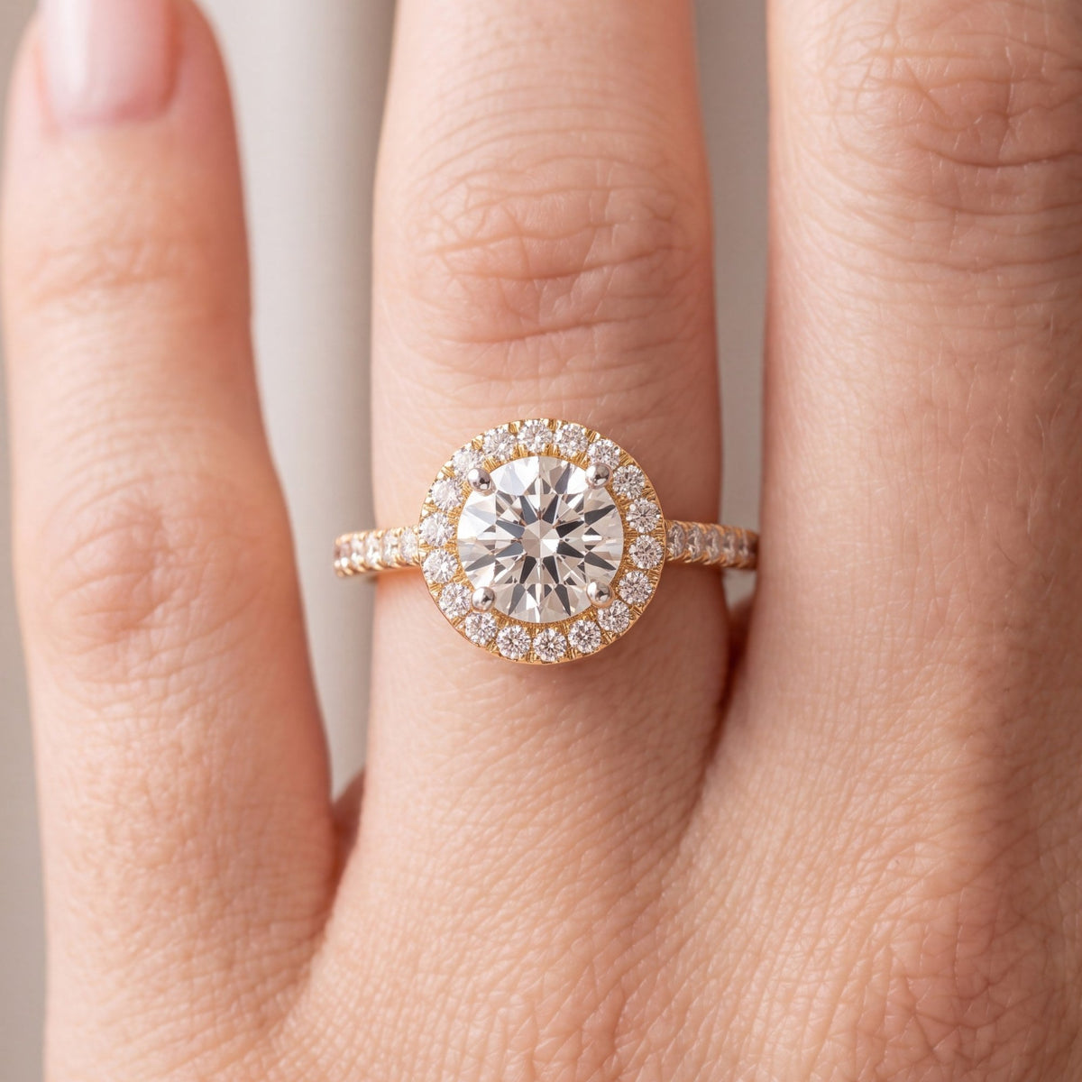 Close-up van de ronde halo verlovingsring met pavé band 1.5 ct in 14k geelgoud aan de hand