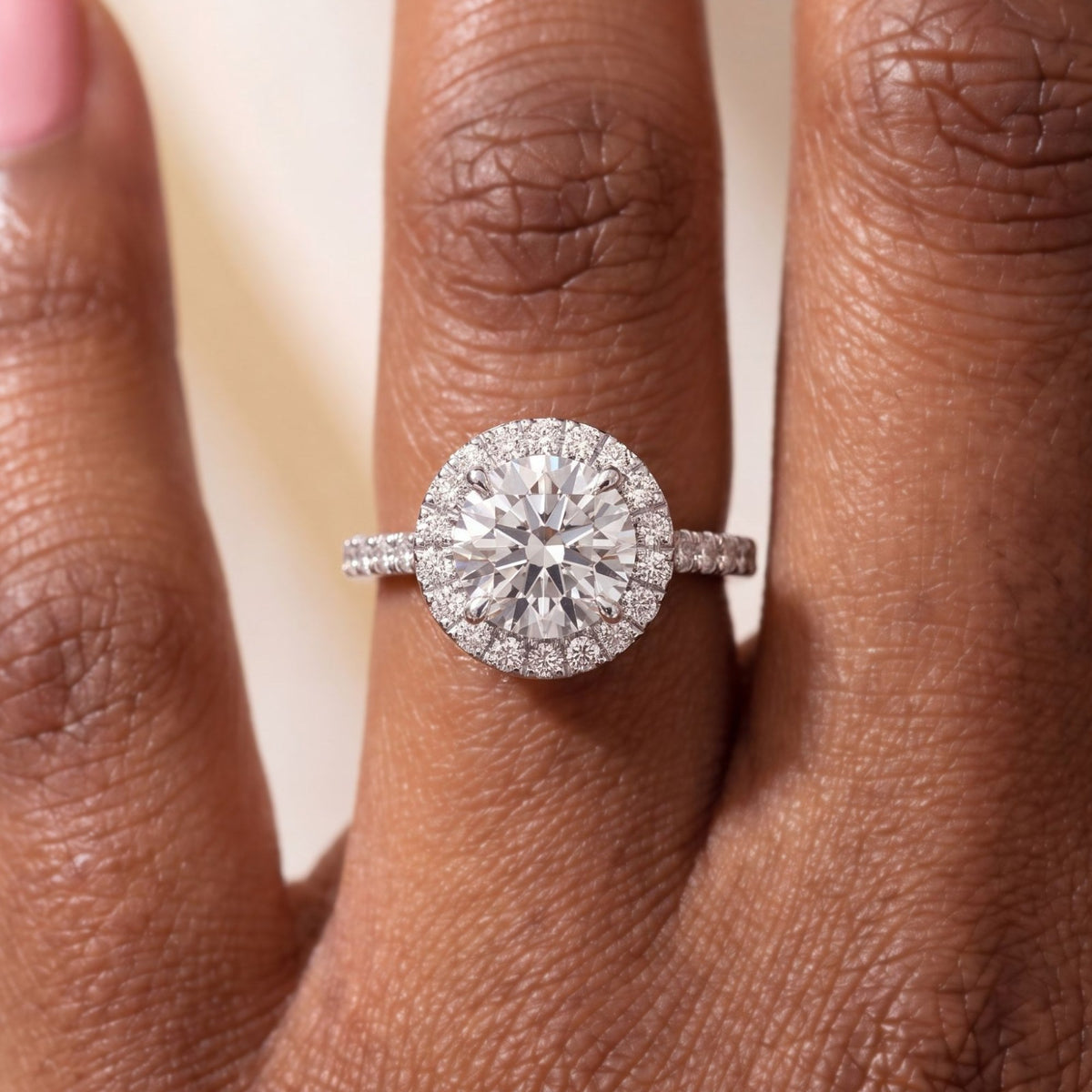 Close-up van de ronde halo verlovingsring met pavé band 1.5 ct in 14k witgoud aan de hand