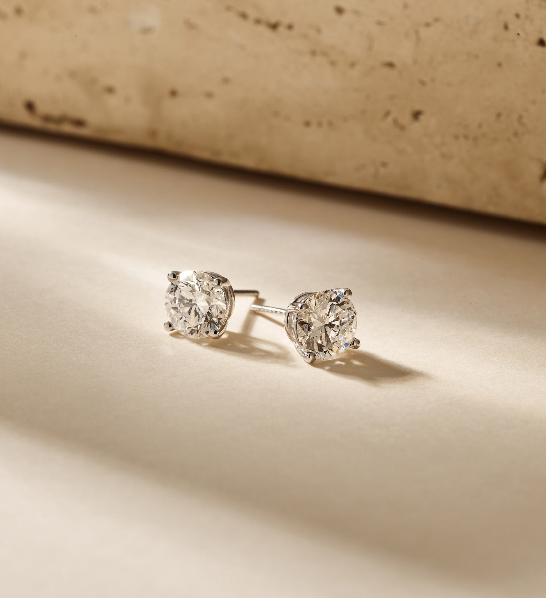 Louen Diamonds solitaire oorstekers 4 pins 14k witgoud met 2.5ct diamant in totaal als sfeerbeeld op zachte achtergrond