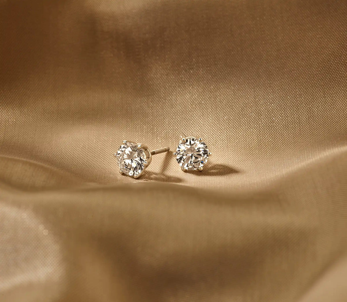 Louen Diamonds solitaire oorstekers zes pins 14k witgoud met 2.5ct diamant in totaal als sfeerbeeld op zachte achtergrond