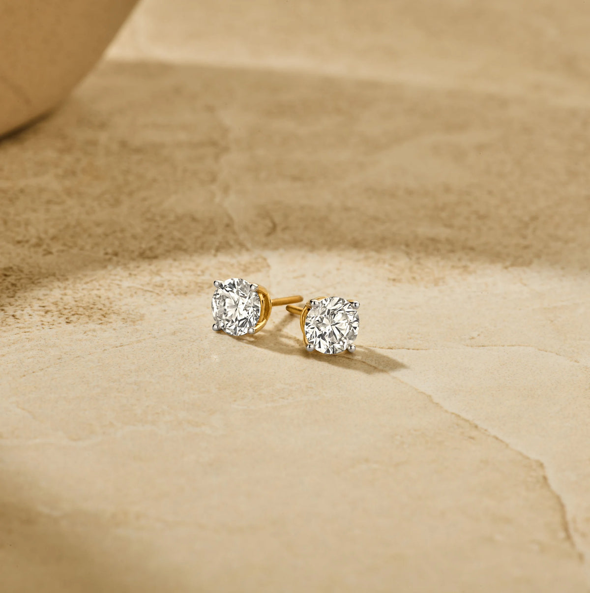 Louen Diamonds solitaire oorstekers 4 pins 14k geelgoud met 2.5ct diamant in totaal als sfeerbeeld op zachte achtergrond