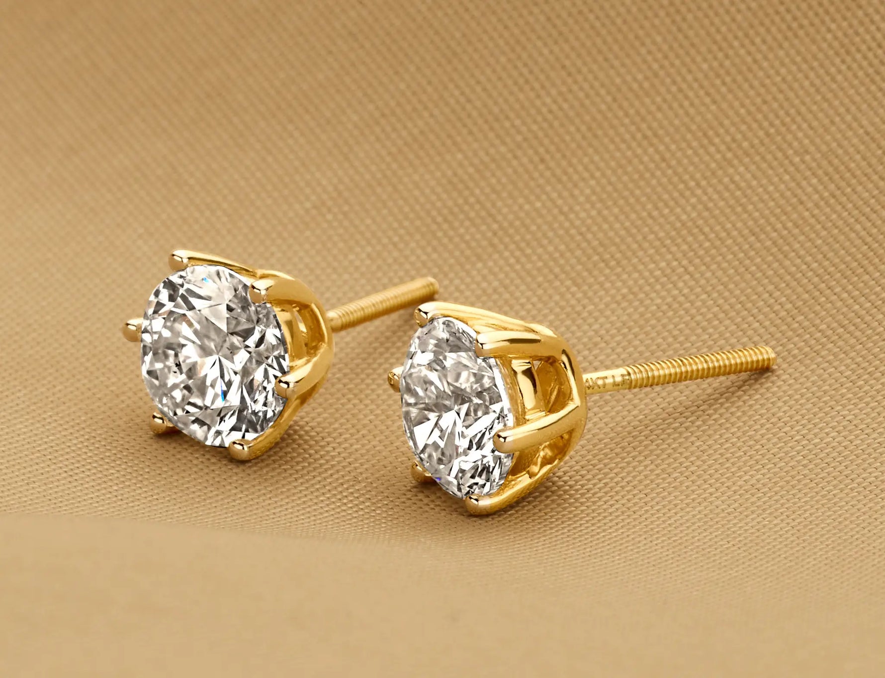 Louen Diamonds solitaire oorstekers zes pins 14k geelgoud met 2.5ct diamant in totaal als sfeerbeeld op zachte achtergrond