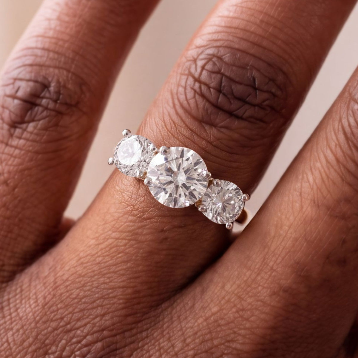Ronde trilogie verlovingsring 3.0 ct in 14k geelgoud aan de hand, op ware grootte (stenen 7,3 + 2× 5,8 mm)