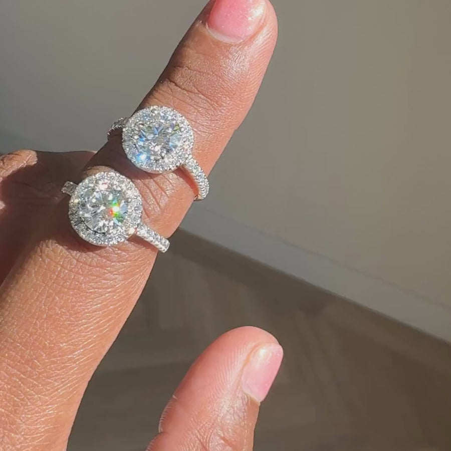 Ronde halo verlovingsring met pavé band 1.5 ct in witgoud en geelgoud naast elkaar aan de hand
