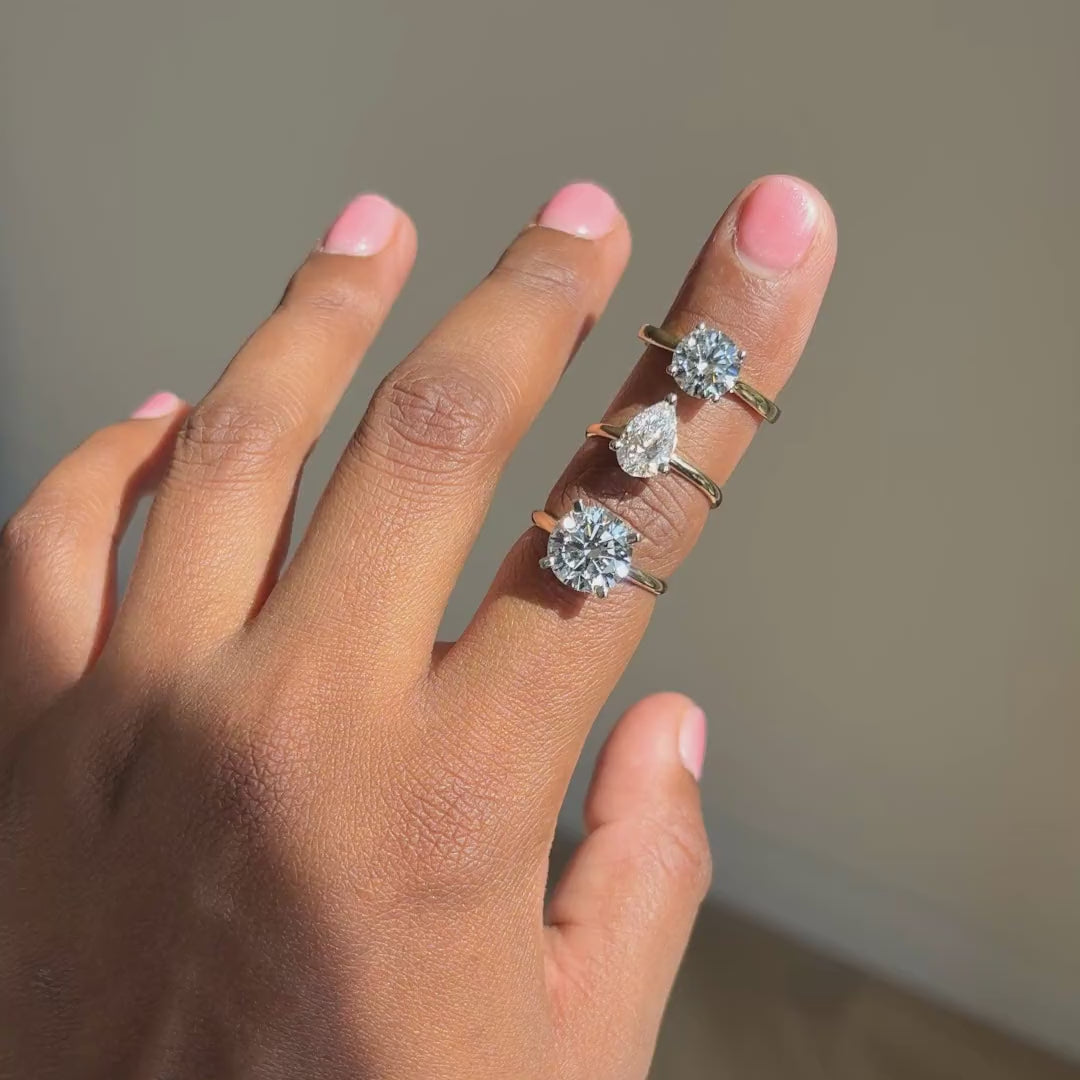 Geelgouden solitaire verlovingsringen 4.0 ct, peervormig 2.0 ct en rond 2.0 ct naast elkaar aan de hand