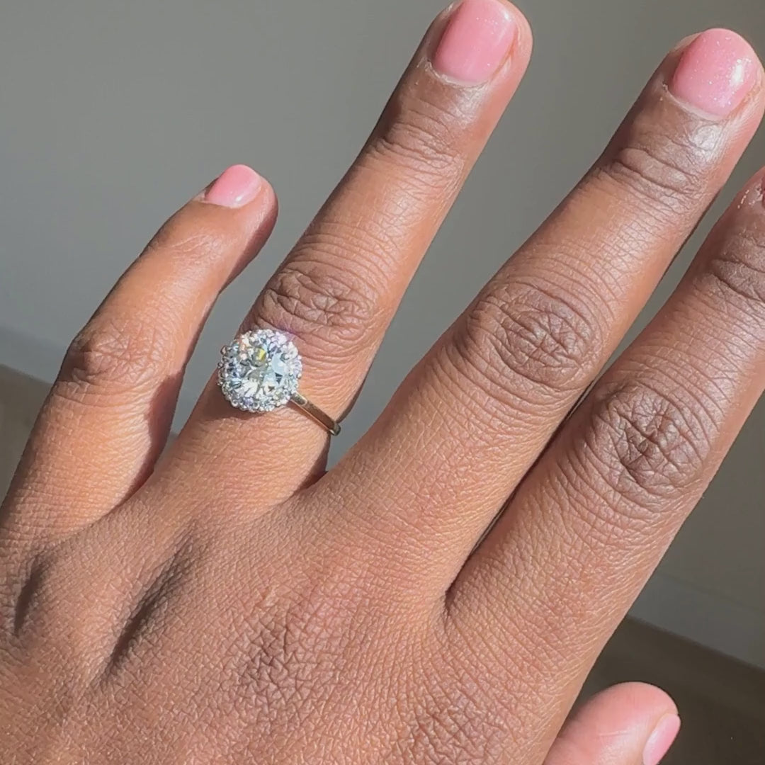 Ronde halo verlovingsring 1.75 ct geelgoud aan de hand